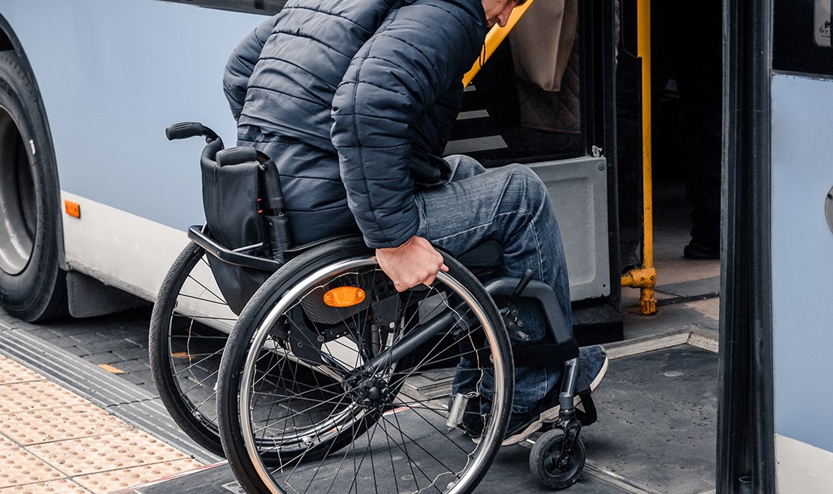 A man pushing the wheels of his wheelchair into a community vehicle. 