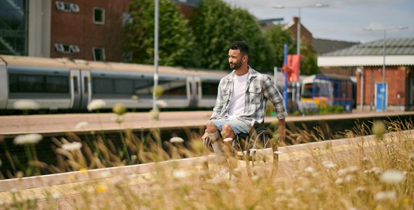 A man in a wheelchair is on a train station platform on a sunny day
