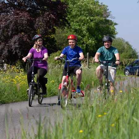 A boy, women and man are riding bicycles.