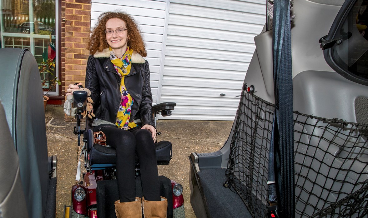 Hannah has fantastic curly hair and looks really happy as she moves her powered wheelchair into a wheelchair accessible vehicle