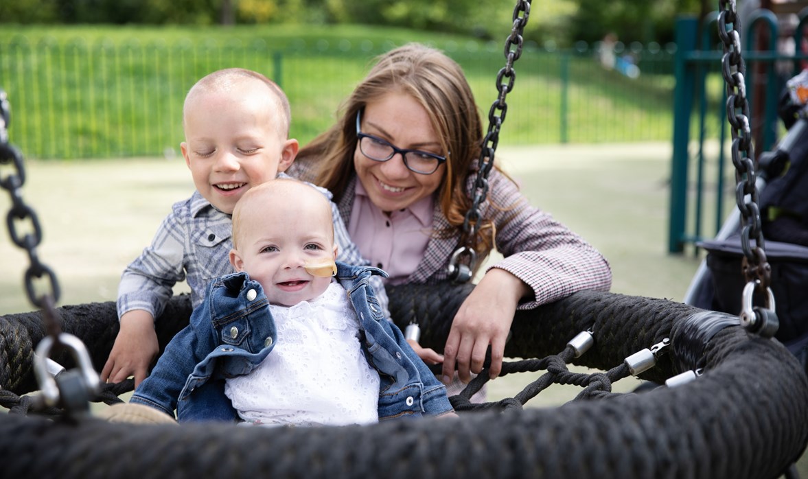 It's all smiles as Danielle plays with her son and daughter, sitting them in a playground basket swing  