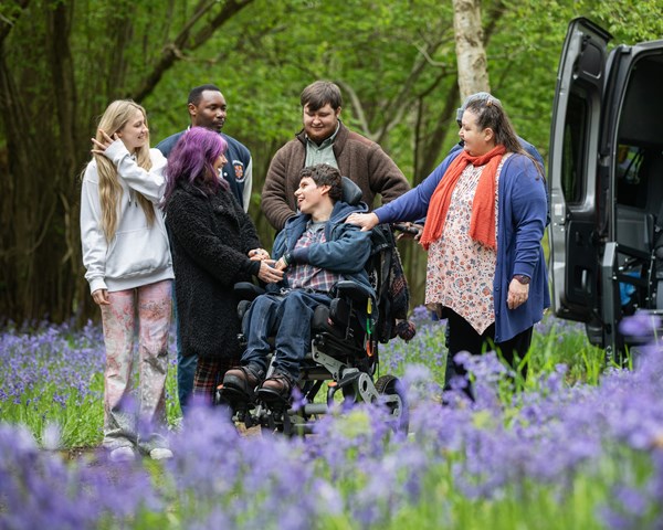A boy in a wheelchair. three women and two men are smiling.
